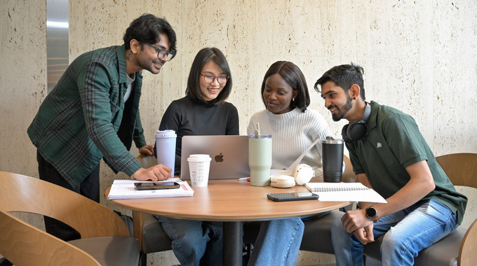 Four students smiling at a table.