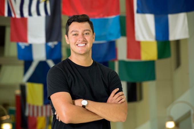 Male student posing in front of international flags