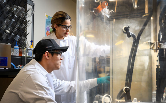 Two students operating lab equipment.