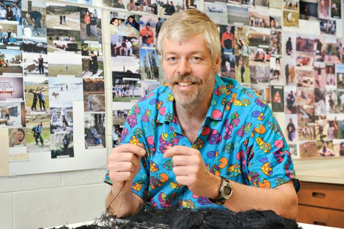 Dr. Mark Brigham sitting at desk in his office with photographys in background.
