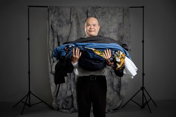 Man holding a lot of fast fashion clothing in his arms.