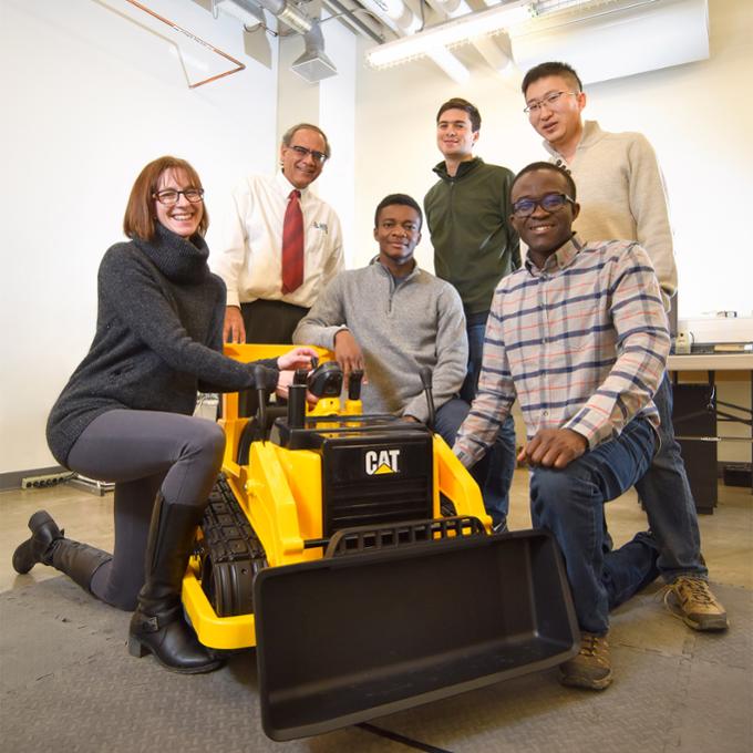 Kim Schaan and  Engineering professor Raman Paranjape with graduate students Victor Okonkwo, Juan Echavarria, Haijun Gao and Tokini Briggs with a motorized toy car they created for children who can't move on their own. 