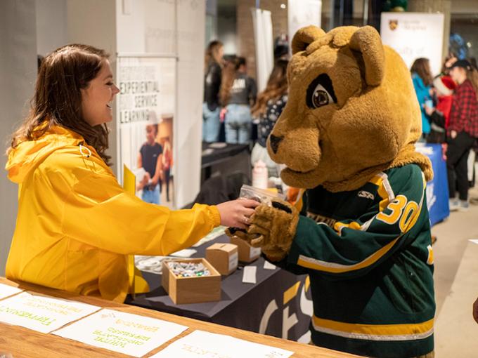 A student is laughing with the U of R Cougar mascot